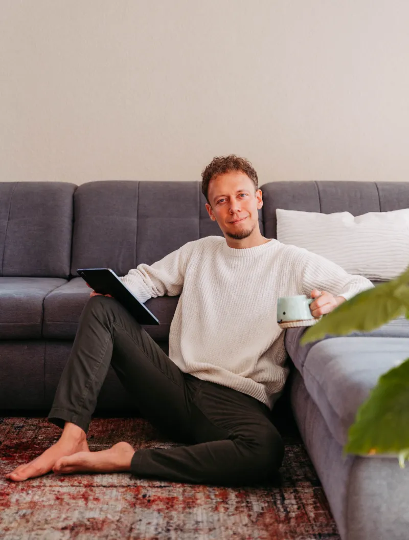 Alex sitzt in seinem Wohnzimmer mit iPad in der Hand